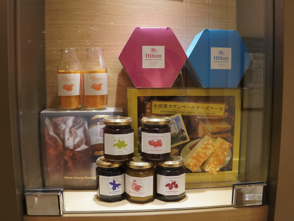 a glass display case with jars of jam and boxes