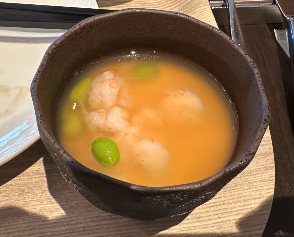 a bowl of soup with shrimp and peas