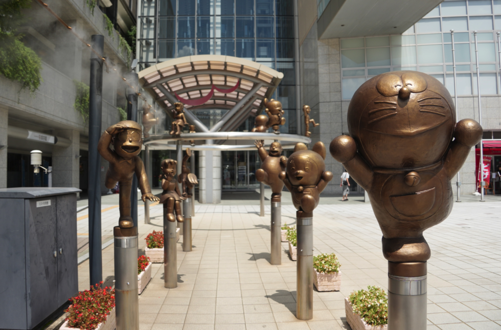 a group of bronze statues in front of a building, Doraemon