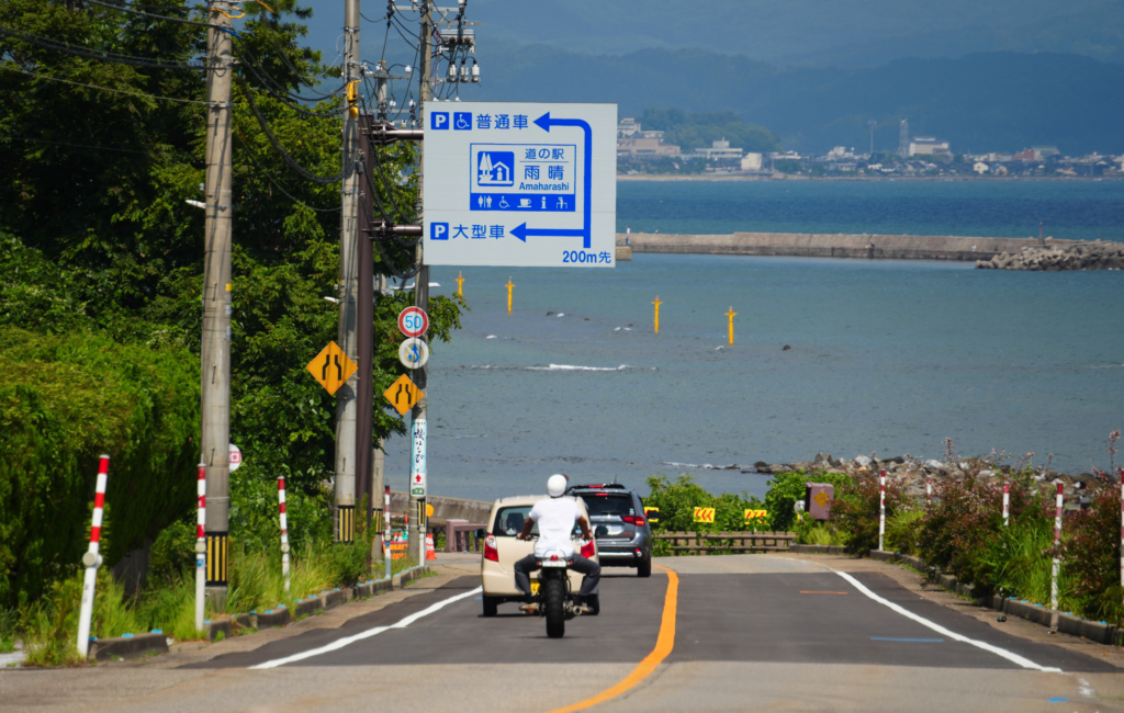 a person riding a motorcycle on a road next to a body of water